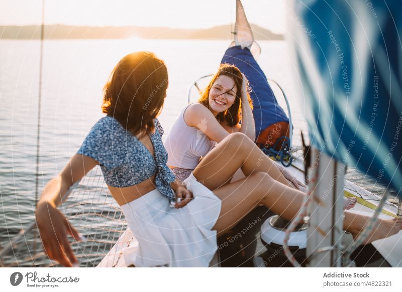 Glückliche Frauen unterhalten sich während einer Kreuzfahrt auf dem Meer bei Sonnenuntergang Segelboot Freund MEER Sommer Urlaub Zusammensein Jacht Lächeln