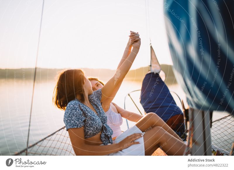 Inhalt Reisende Freundinnen halten sich auf einer Yacht bei Sonnenuntergang an den Händen Frauen Händchenhalten Jacht Kreuzfahrt MEER Segelboot Freundschaft