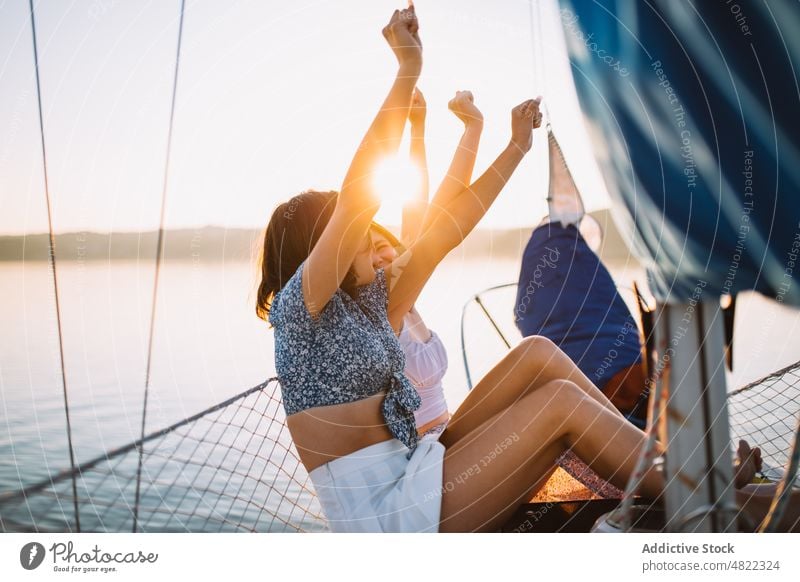 Glückliche Frauen unterhalten sich während einer Kreuzfahrt auf dem Meer bei Sonnenuntergang Segelboot Freund MEER angehobene Arme Sommer Urlaub Zusammensein