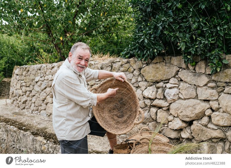 Älterer männlicher Handwerker prüft Weidenkorb auf dem Bauernhof Mann Korb esparto Gras Landschaft untersuchen Zeigen Kunstgewerbler Meister Tradition