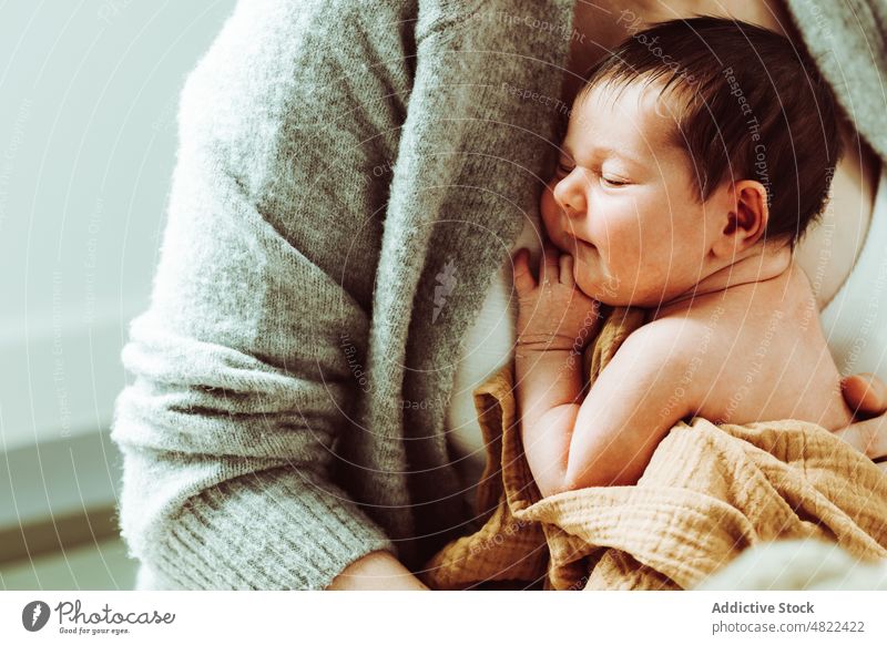 Crop Mutter umarmt neugeborenes Baby in weißen Studio Frau Umarmung Liebe Mutterschaft Umarmen Pflege Windstille bezaubernd Säugling Kindheit jung Mama