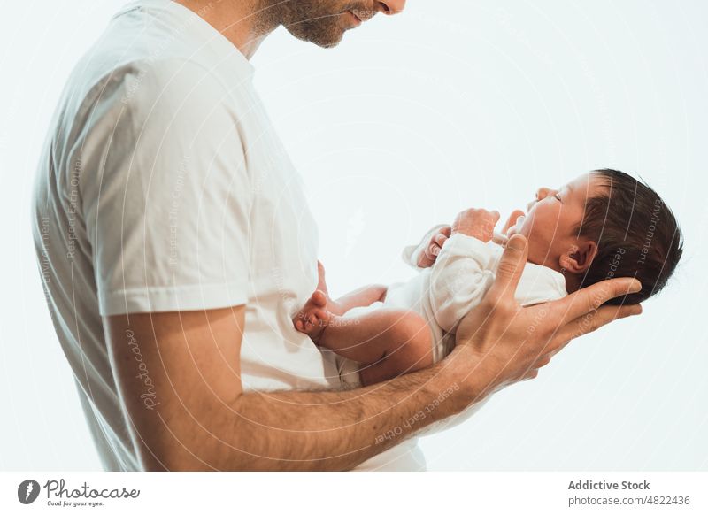 Crop unerkennbar Vater hält niedlichen Baby gegen weißen Hintergrund Mann Liebe neugeboren Halt bezaubernd Kinderbetreuung Zusammensein unschuldig Umarmen