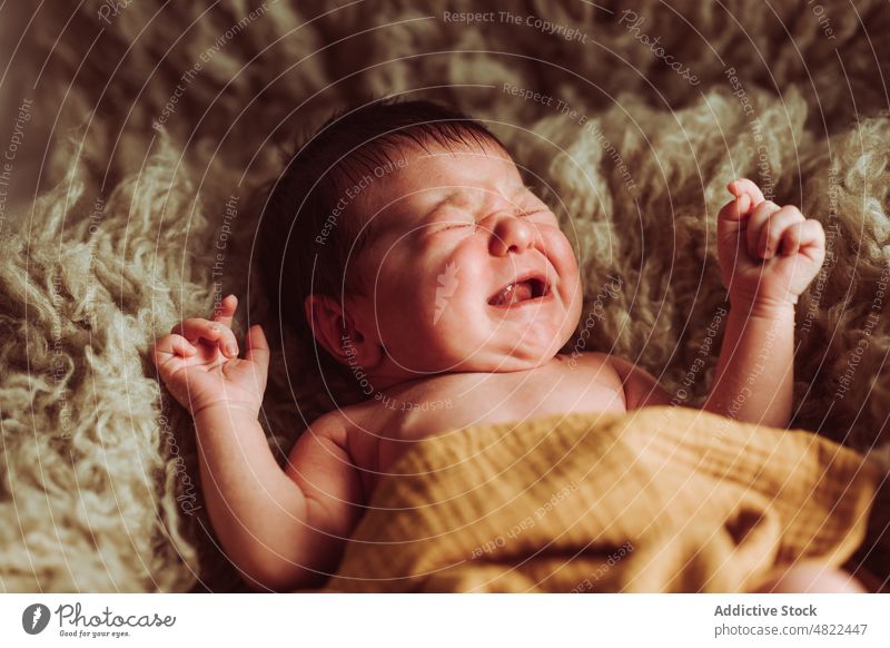 Niedliches Baby auf Felldecke liegend und weinend Augen geschlossen Lügen bezaubernd unschuldig verärgert neugeboren Säuglingsalter Komfort süß Schlafzimmer