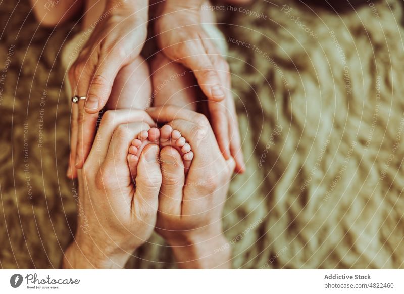 Crop gesichtslose Eltern berühren die Füße eines niedlichen Säuglings Familie Baby Mutter Vater Streicheln Liebe Umarmung neugeboren Fuß Papa Mama Generation