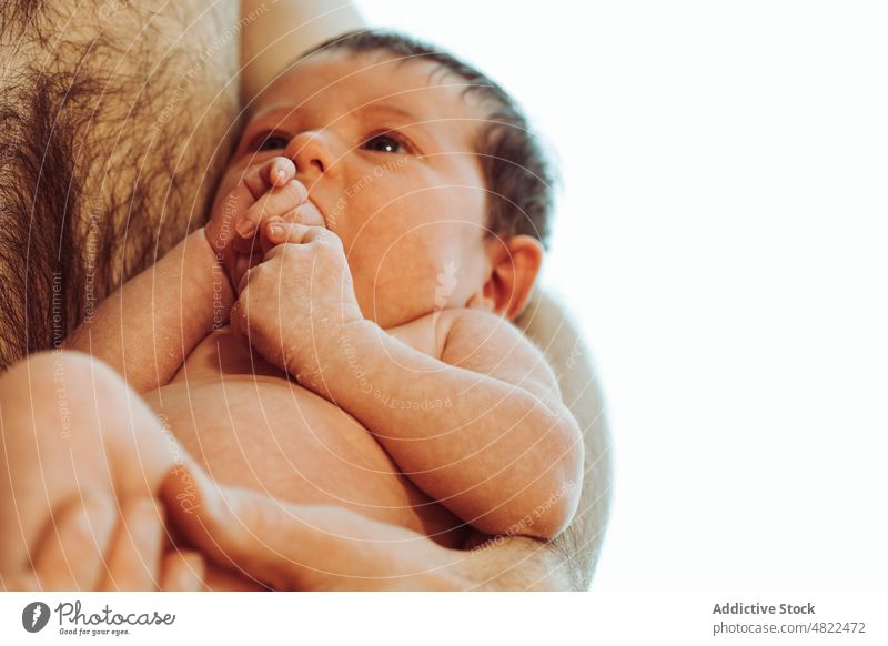 Niedlicher Säugling saugt an der Hand, während er von Papa im weißen Studio gehalten wird Baby Mann Vater saugen Liebe neugeboren Umarmung Vaterschaft Angebot