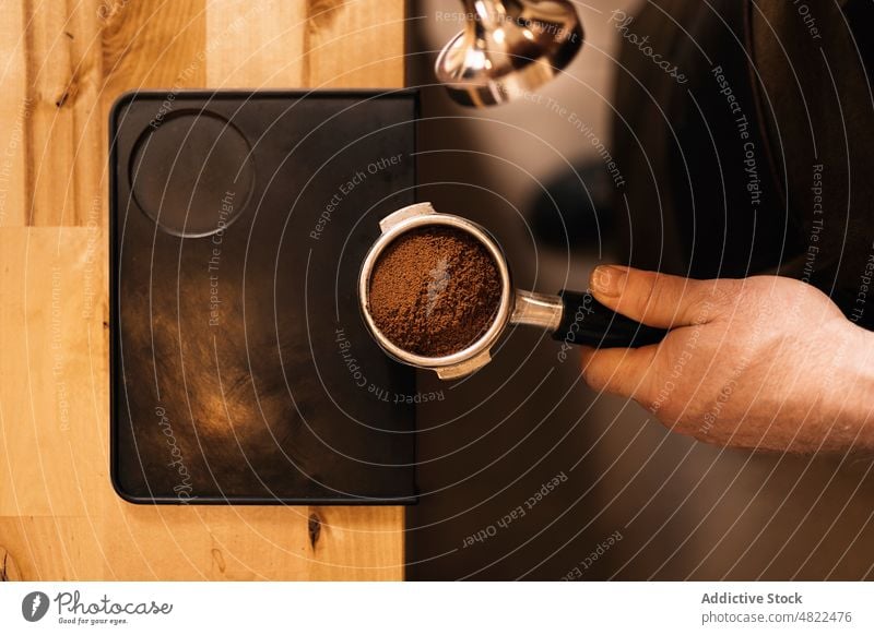 Anonymer Mann mit Tamper zum Pressen von gemahlenem Kaffee im Filter Portafilter Espresso sich[Akk] zu schaffen machen Barista Café Kaffeehaus vorbereiten Boden