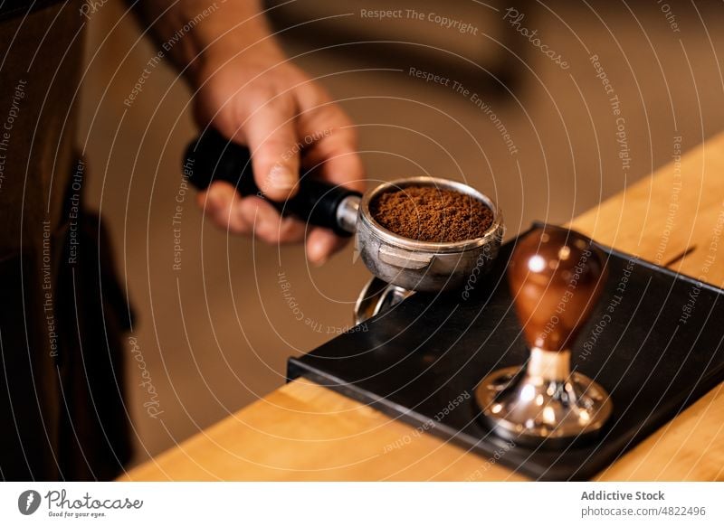 Anonymer Mann, der einen Tamper benutzt, um gemahlenen Kaffee in einen Siebträger zu pressen Portafilter Presse Espresso sich[Akk] zu schaffen machen Barista