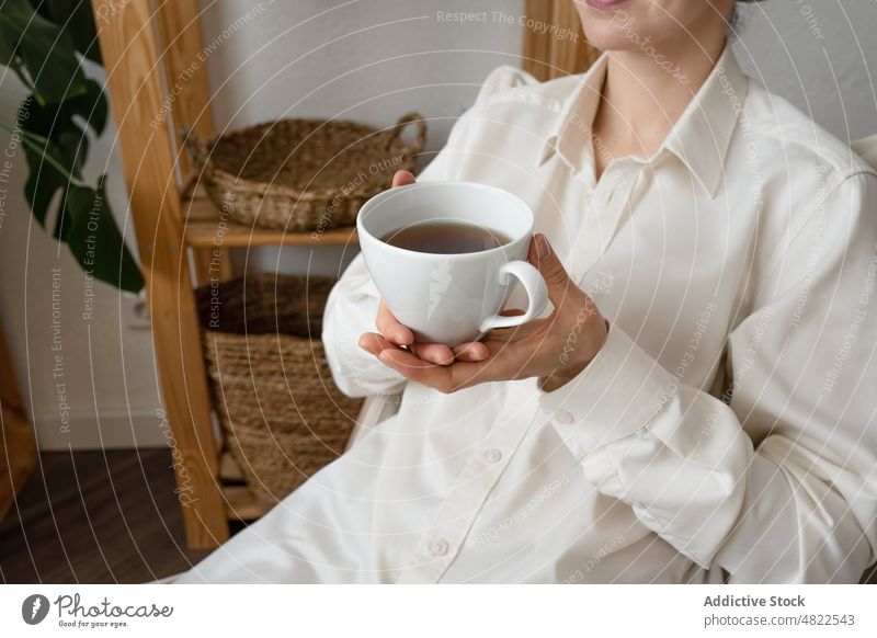 Anonyme Dame sitzt auf einem Stuhl und trinkt Kaffee am Morgen Frau trinken ruhen heimwärts Glück Pflanze Appartement Getränk genießen Erholung jung lässig