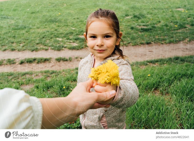 Kind schenkt seiner Mutter im Park gepflückte Blumen Frau Mädchen Löwenzahn präsentieren Zeit verbringen Zusammensein Natur Geschenk pflücken Landschaft Wiese