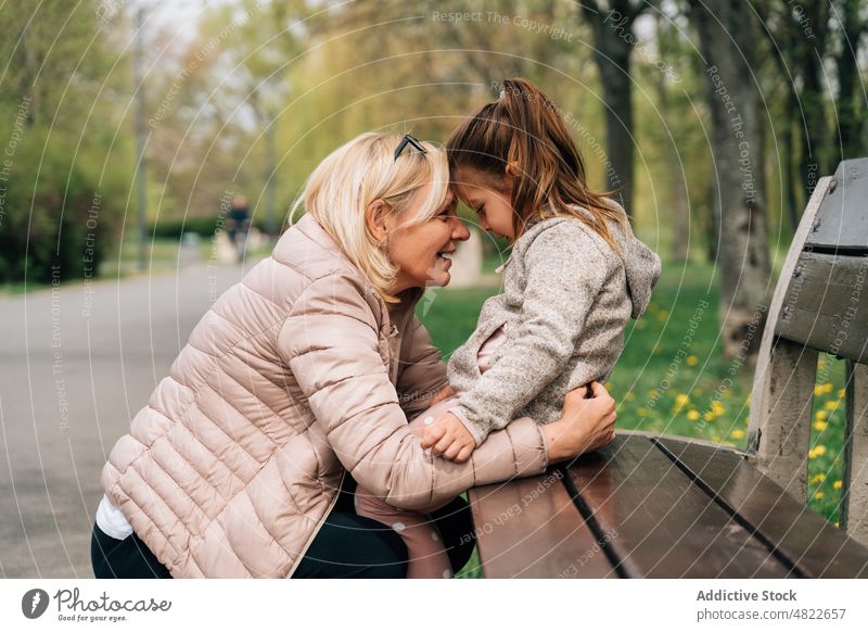 Reife Oma umarmt süßes Mädchen im Park Frau Kind Enkelin Umarmen Liebe Großmutter Partnerschaft Glück Bonden Zusammensein reif warme Kleidung Baum kuscheln