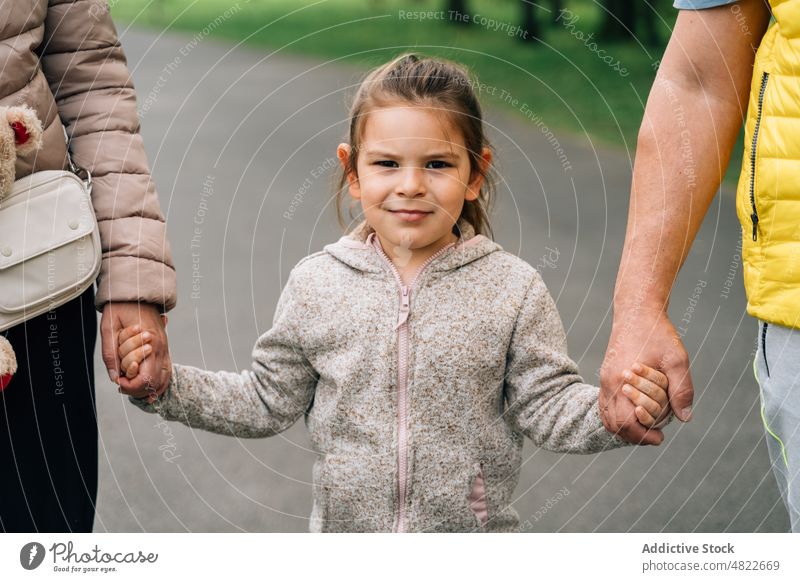 Fröhliches kleines Kind hält die Hände der Großeltern im Park Händchenhalten Spaziergang Glück Zeit verbringen Zusammensein Enkelin Partnerschaft heiter Freude