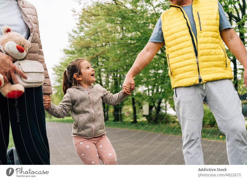 Fröhliches kleines Kind hält die Hände der Großeltern im Park Händchenhalten Spaziergang Glück Zeit verbringen Zusammensein Enkelin Partnerschaft heiter Freude