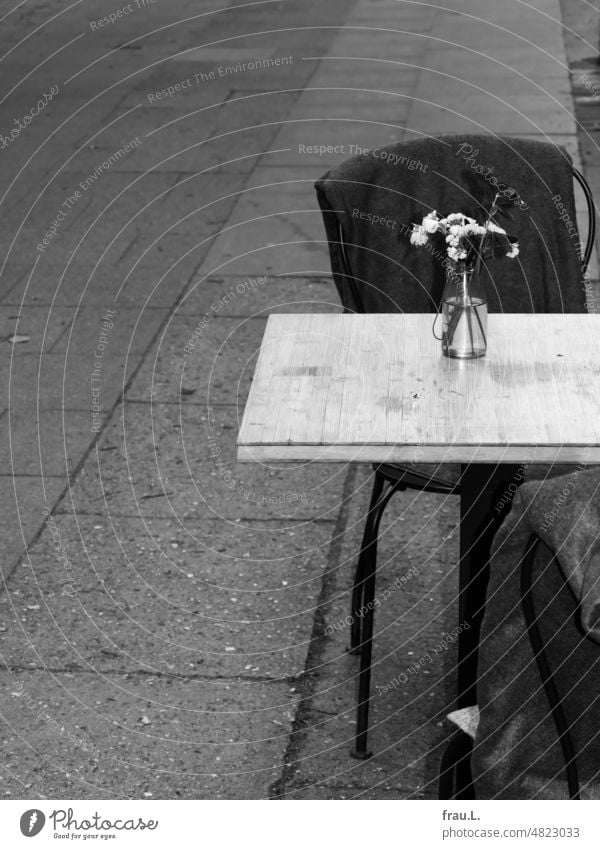 Tisch mit Blumenstrauß Straßencafé Dekoration Blüte Pflanze Stuhl Wolldecke Bistro Café Bürgersteig trist trostlos Stadt urban Konditorei Restaurant ungemütlich