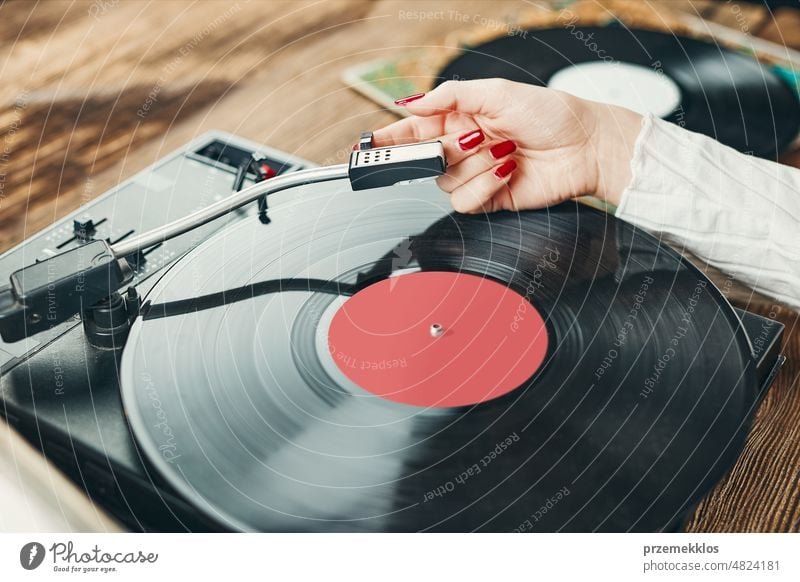 Junge Frau hört Musik von einem Schallplattenspieler. Spielt Musik auf einem Plattenspieler. Frau genießt Musik aus alter Plattensammlung zu Hause hören