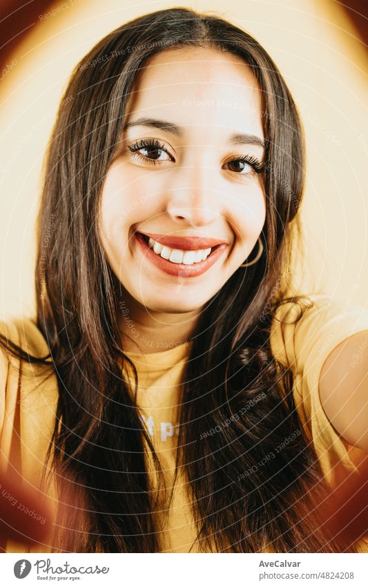 Junge Brünette Mädchen über isolierten gelben Hintergrund, die ein Selfie und zeigt Zunge in die Kamera, während Spaß zu haben. Glückliche Frau. Menschen aufrichtige Gefühle Lebensstil Konzept