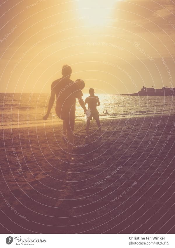 Die Silhouetten von zwei Jugendlichen, die am Strand Ball spielen. 2 Jugendliche Sommer Meer Wasser Sonne Gegenlicht schönes Wetter Urlaub Spielen Freude Sand