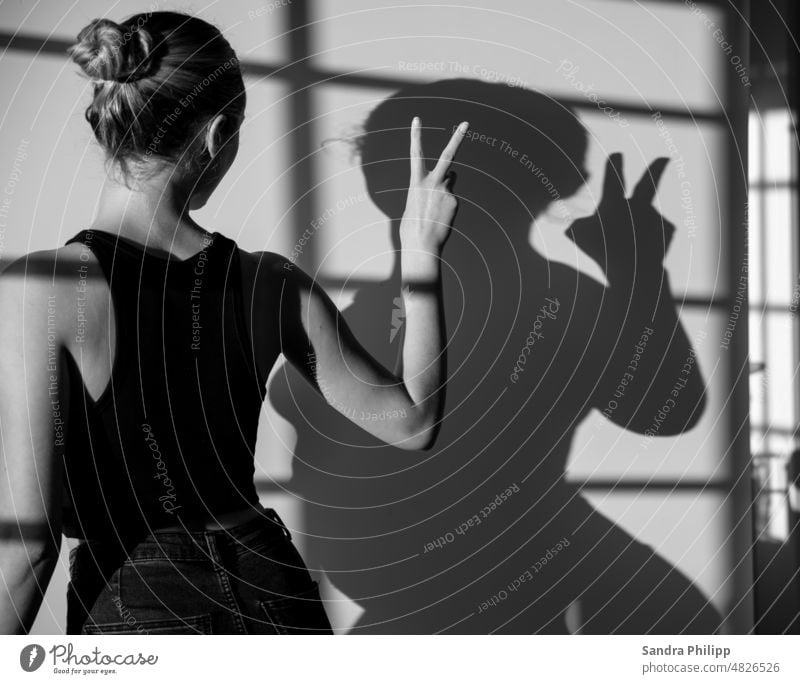 Portrait einer jungen Frau mit ihrem Schatten macht das Victoryzeichen portrait junge Frau Mensch feminin langhaarig natürlich 18-30 Jahre schön schlank