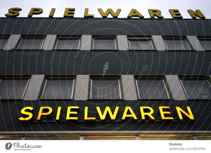 Gelbe Leuchtschrift an einem traditionellen Geschäft für Spielwaren in einem typischen Gebäude der Nachkriegszeit am Abend im Stadtteil Bornheim in Frankfurt am Main in Hessen