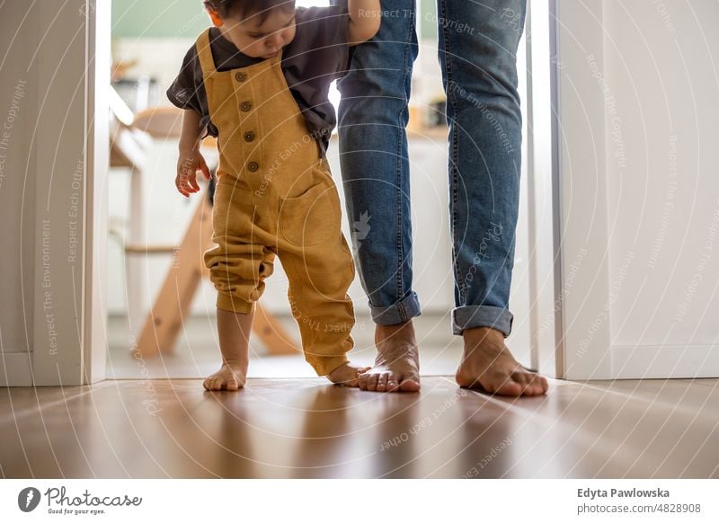 Kleiner Junge lernt zu Hause mit seinem Vater das Laufen laufen Stehen aktiv Erwachsener Zuneigung Baby Barfuß Bonden offen Pflege lässig heiter Kind Kindheit
