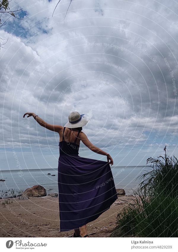 Frau tanzt in einem Kleid Bewegung Sommerurlaub Einsamkeit Szene Ausflugsziel Landschaft Textfreiraum Erkundung Sommerhut Mode purpur Strand