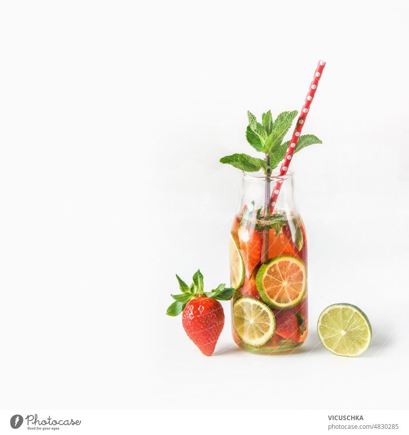 Limonade in Flasche mit Trinkhalm und Zutaten: Erdbeere und Limettenscheibe auf weißem Hintergrund. Erdbeeren weißer Hintergrund Sommer Erfrischungsgetränk