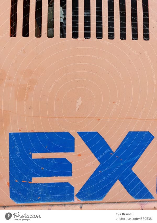 Das Wort EX in blauer Farbe auf orangen Grund, am oberen Rand Lüftungsschlitze Buchstaben Schriftzeichen