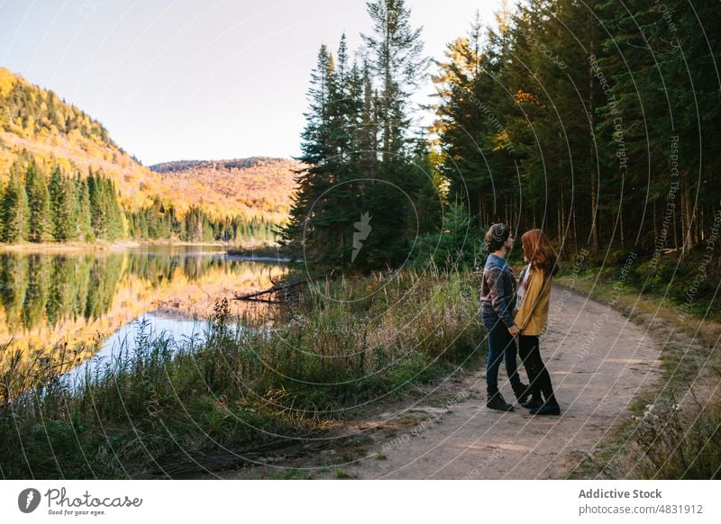 Verliebtes Paar kuschelt am Seeufer an einem Herbsttag Umarmen Wald Ausflug Liebe bewundern Umarmung reisen Partnerschaft romantisch Landschaft Natur Freund