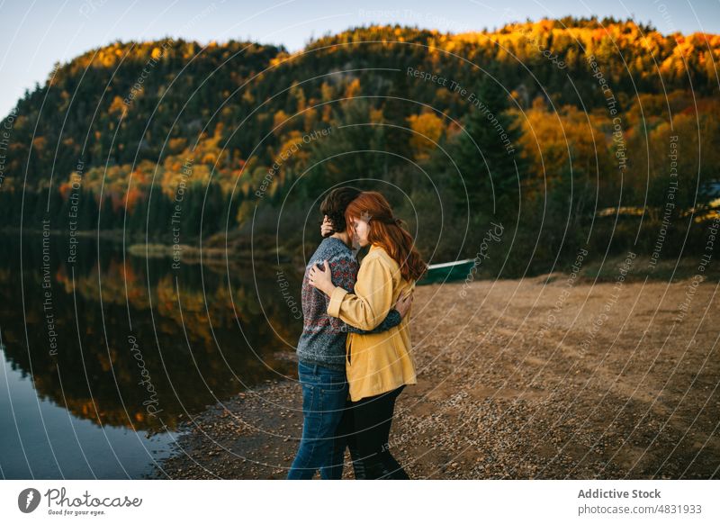 Verliebtes Paar kuschelt am Seeufer an einem Herbsttag Umarmen Wald Ausflug Liebe bewundern Umarmung reisen Partnerschaft romantisch Landschaft Natur Freund
