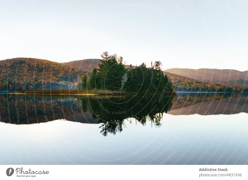 Ruhiger See, umgeben von Bergen mit Herbstbäumen bei Sonnenuntergang Berge u. Gebirge Baum Natur Landschaft Wald nadelhaltig Ufer Reflexion & Spiegelung