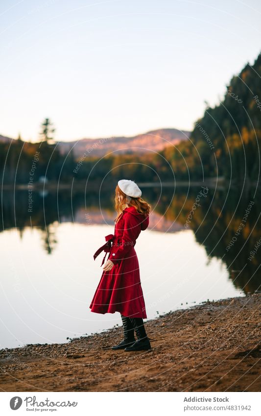 Weiblicher Tourist bewundert üppige Herbstbäume, die einen See in der Natur umgeben Frau bewundern Landschaft Fernweh Reisender Wald Baskenmütze Ausflug