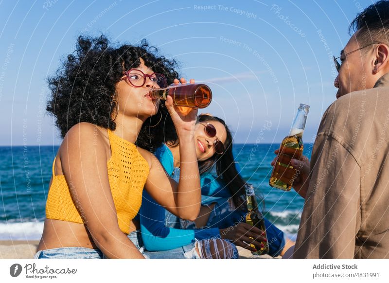 Schwarze Frau trinkt Bier mit Freunden trinken Strand MEER Flasche Zusammensein Wochenende Sommer ruhen Frauen Mann vielfältig rassenübergreifend multiethnisch