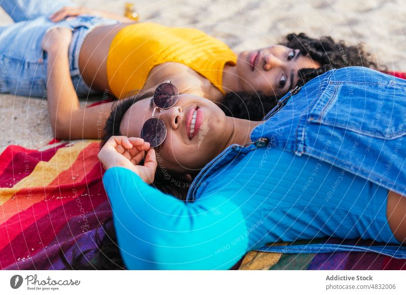Gerne diverse Freundinnen auf Decke am Strand Frauen Lächeln Wochenende Zusammensein Sommer Glück farbenfroh Porträt ruhen Kälte heiter vielfältig