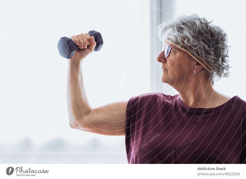 Starke ältere Frau, die mit einer Hantel trainiert Übung Kurzhantel Bizeps Training Fitness Morgen heimwärts stark Gewicht gealtert Senior Rentnerin