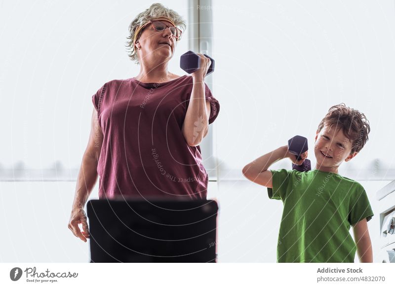 Großmutter und Enkel trainieren mit Kurzhanteln mit Video-Tutorial Übung heimwärts Fitness Training Küche Zusammensein Frau Gerät Junge Senior gealtert Tablette