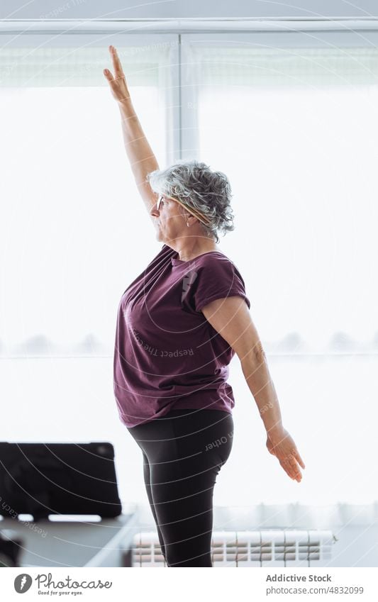 Ältere Frau beim morgendlichen Sport Übung Dehnung Morgen heimwärts gymnastisch Arm angehoben Training früh Fitness älter Senior gealtert sonnenbeschienen