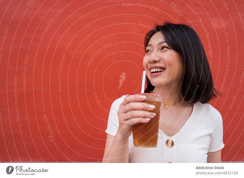 Junge ethnische Frau trinkt ein erfrischendes Getränk zum Mitnehmen auf der Straße trinken Kaffee Erfrischung Imbissbude Porträt selbstbewusst Stil Stroh jung
