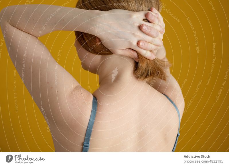 Anonyme kurvige Frau hält die Hände hinter dem Kopf, während sie in der Nähe einer gelben Wand steht körperpositiv Hand hinter dem Kopf Übergröße Model Figur