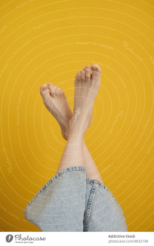Crop gesichtslose barfuß Frau hebt Beine gegen gelbe Wand Barfuß Bein angehoben Beine gekreuzt feminin trendy sich[Akk] entspannen filigran Harmonie sanft