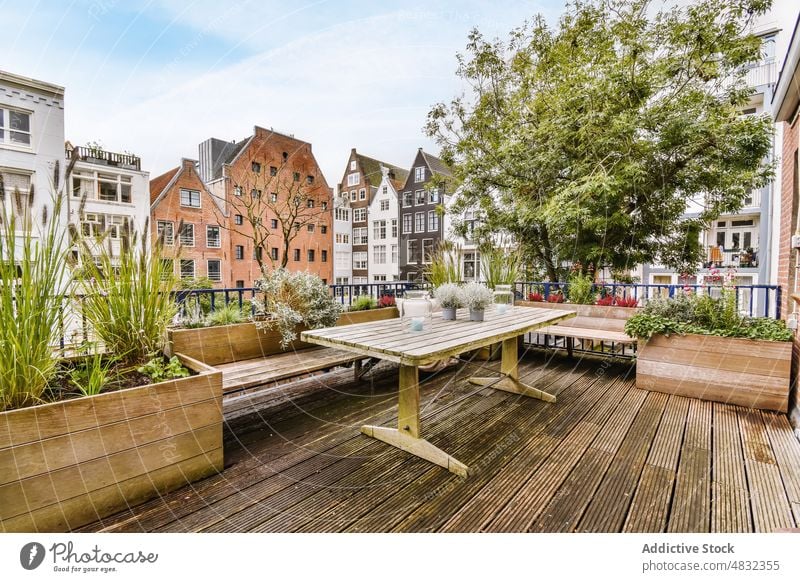 Holztisch auf der großen Terrasse eines Wohnhauses Gebäude Tisch Revier Großstadt wohnbedingt Architektur Veranda gemütlich Pflanze Dekor Viertel verweilen