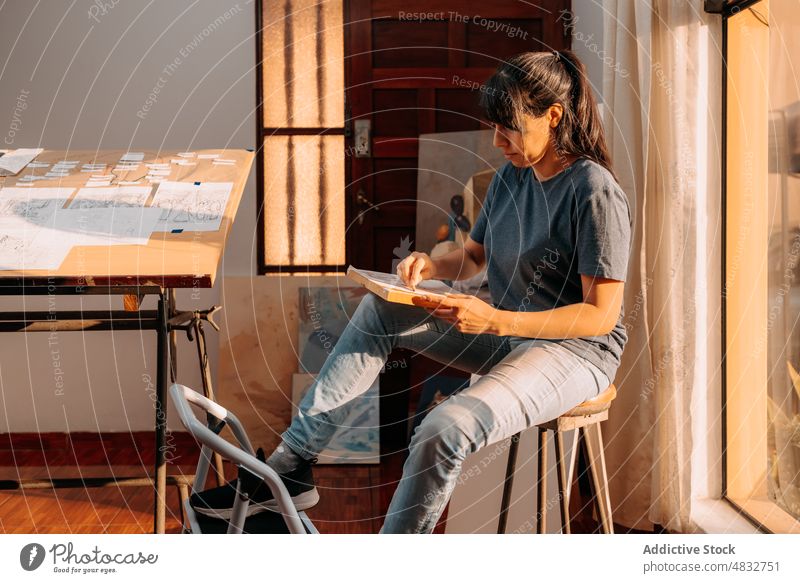 Frau zeichnet auf weißem Papier am Fenster Innenbereich zeichnen Erwachsener Lifestyle kreativ Atelier Arbeitsplatz künstlerisch hübsch Fähigkeit Hobby Kunst