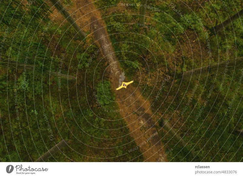 Mann in gelber Regenjacke steht auf einem Weg im Wald - Blick aus einer Drohne Herbst Regenmantel böse Dröhnen märchenhaft Angst Wanderung wandern einsam