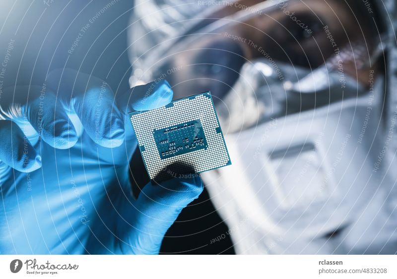 Hochmoderne Elektronikfabrik, Ingenieur in sterilem Schutzanzug hält Mikrochip mit Handschuhen und prüft ihn Halbleiter Mikrochip-Herstellung Nanotechnologie