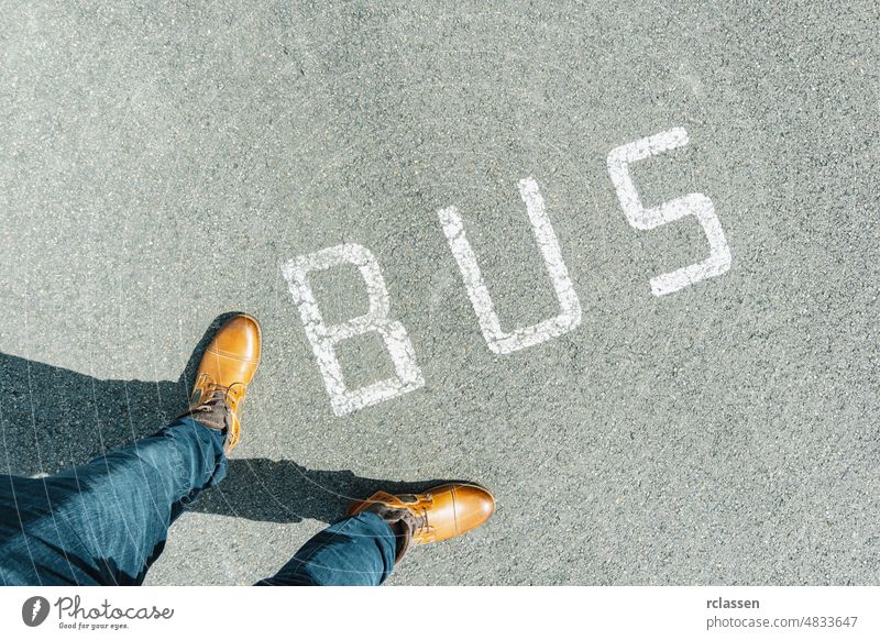 Mann stehend auf grunge Asphalt Stadtstraße mit weißem Text Bus, Punkt der Ansicht Perspektive pov konzeptionell Stock Zeichen urban Schritt Konzept