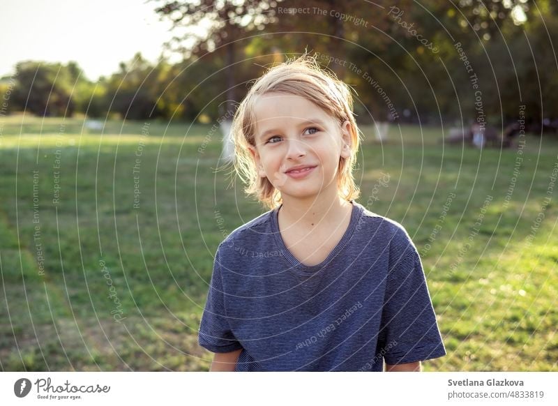 Teenager Junge schaut auf Kamera im Freien Nahaufnahme Lifestyle-Porträt im Park in der Natur. Grünes Gras backgrund Goldene Stunde Sonne Licht Gesicht jung