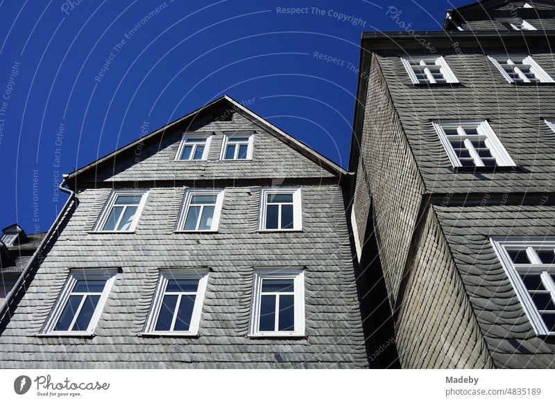 Alte Fassade mit Schindeln aus Schiefer in Grau und Anthrazit vor blauem Himmel im Sonnenschein in den Gassen der Altstadt von Marburg an der Lahn in Hessen