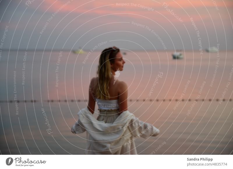 Junge blonde Frau im Sommeroutfit schaut auf das Meer Junge Frau la langhaarig schön Außenaufnahme feminin Haare & Frisuren Wasser Sonnenuntergang Schiffe Boote