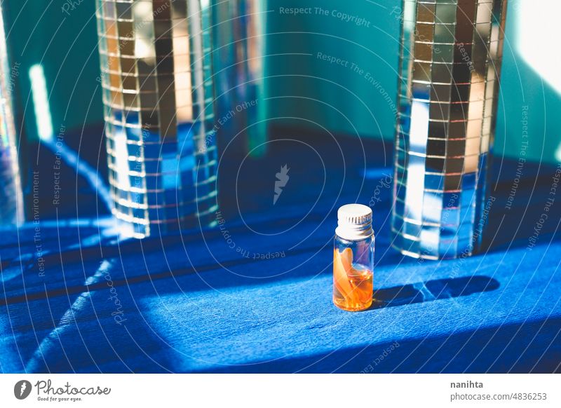 Ein kleines Fläschchen mit essentiellem Öl in einem Disco-Hintergrund-Set Parfüm Erdöl notwendig retro Spiegel altehrwürdig blau Köln Palette orange Flasche