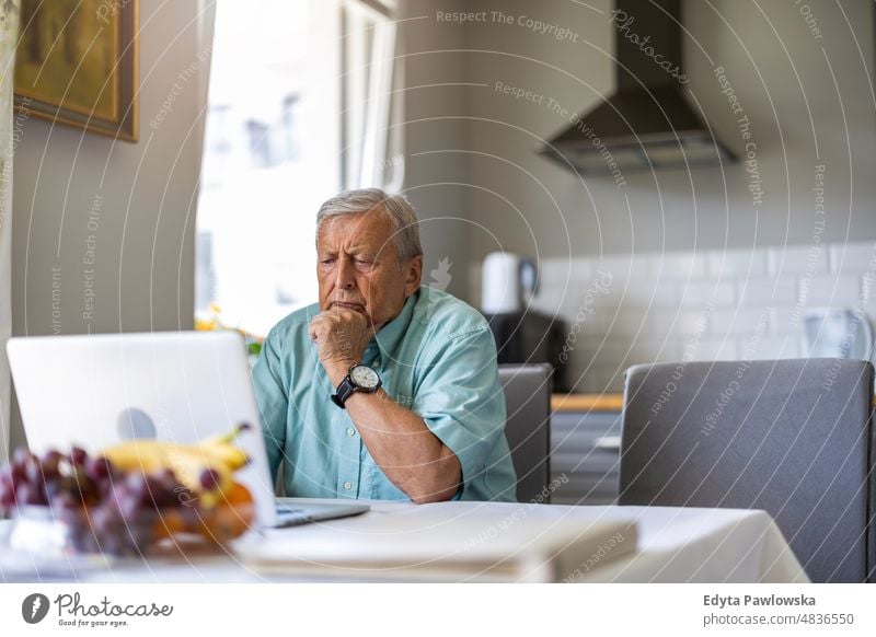 Älterer Mann mit Laptop am Küchentisch älterer Erwachsener gealtert Porträt Person lässig Freizeit Lifestyle Rentnerin Kaukasier in den Ruhestand getreten