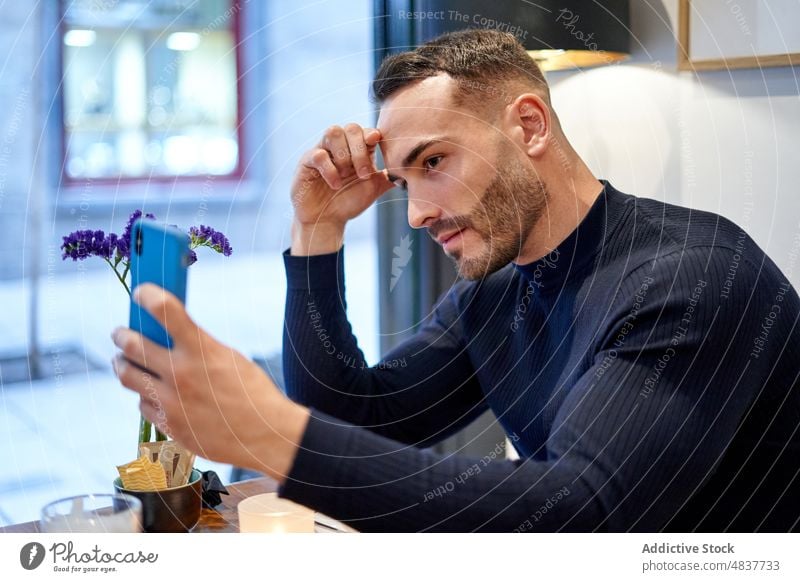 Mann spricht Selfie im Café Selbstportrait Smartphone Stil soziale Netzwerke Hobby Fotografie einfangen modern Tisch Funktelefon Mobile gutaussehend männlich