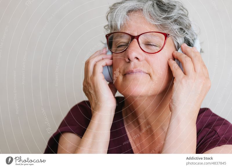Zufriedene ältere Dame, die mit geschlossenen Augen über Kopfhörer Musik hört Frau zuhören Augen geschlossen meloman genießen Gesang Audio Inhalt positiv